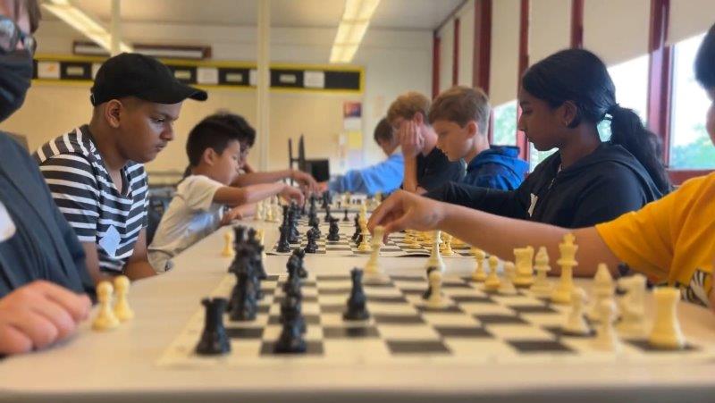 kids sitting at a long table playing chess